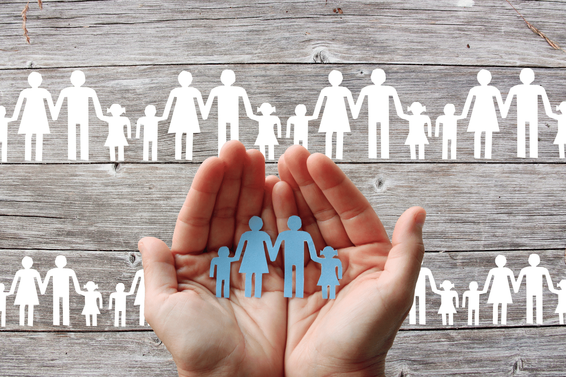hands holding paper cutout of a family