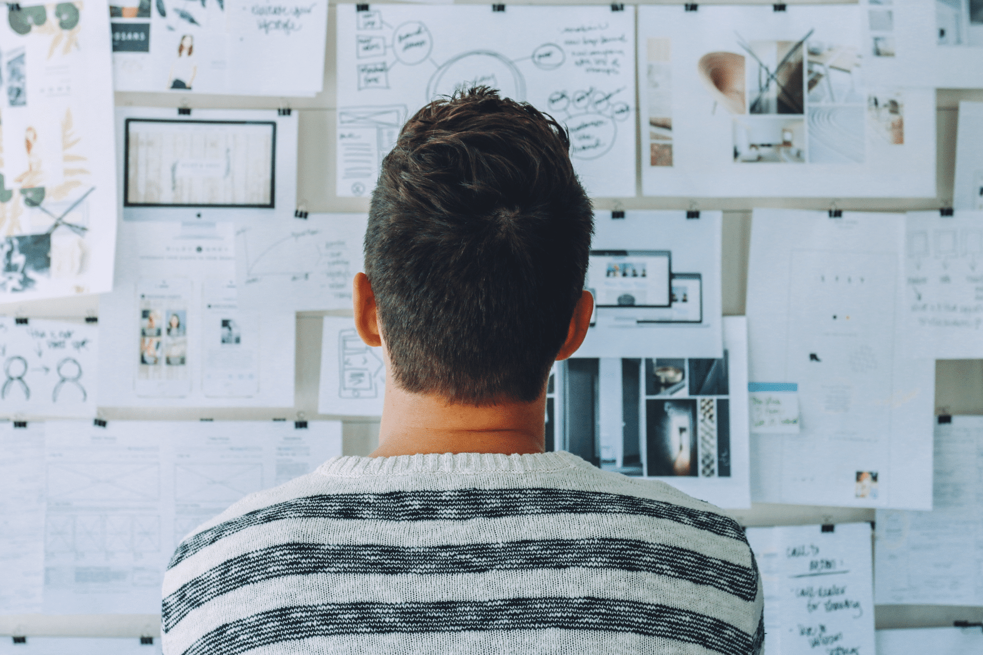 man looking at various business templates posted on a wall