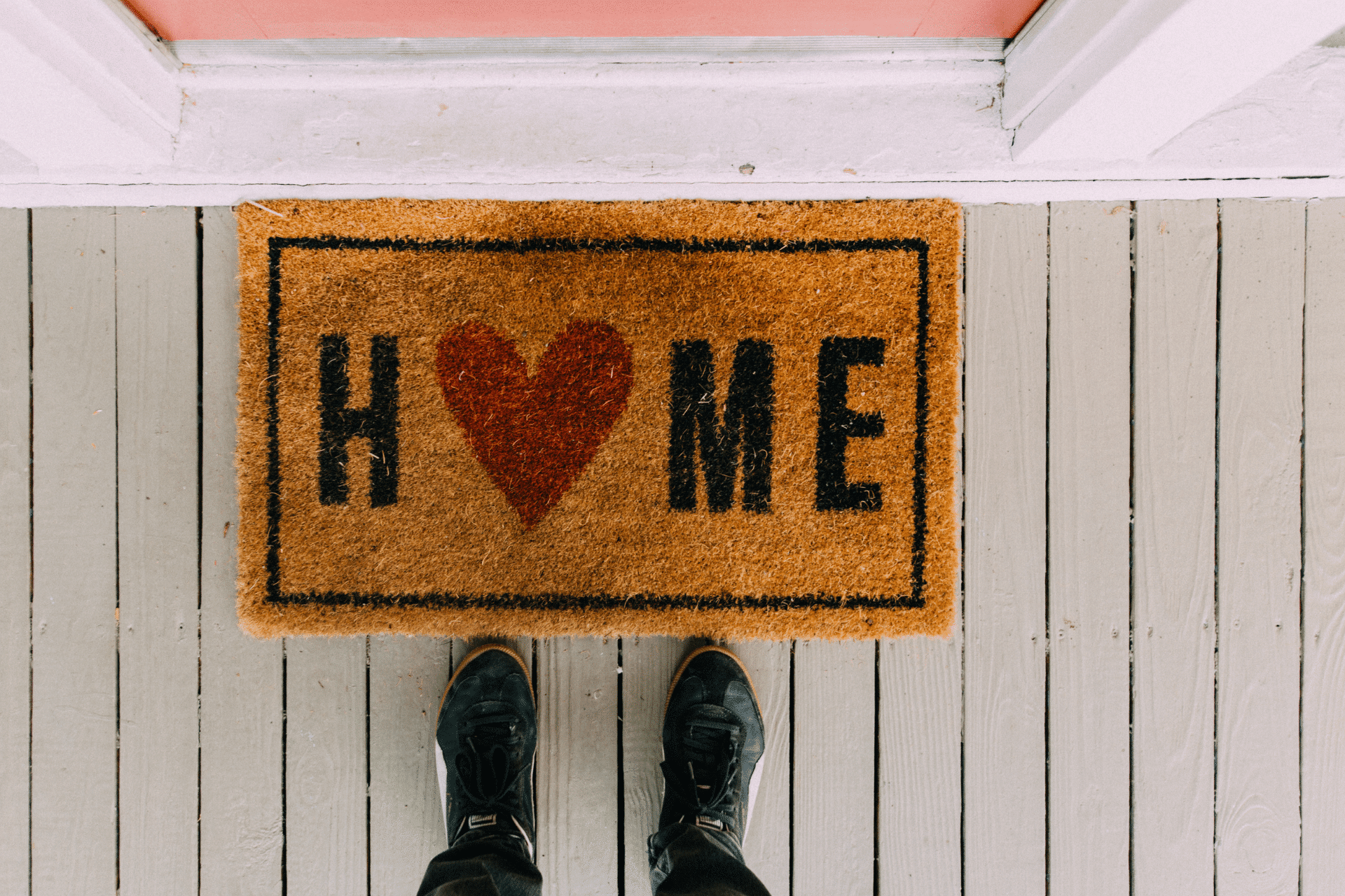 person standing at a front door with a welcome mat that says 'home'